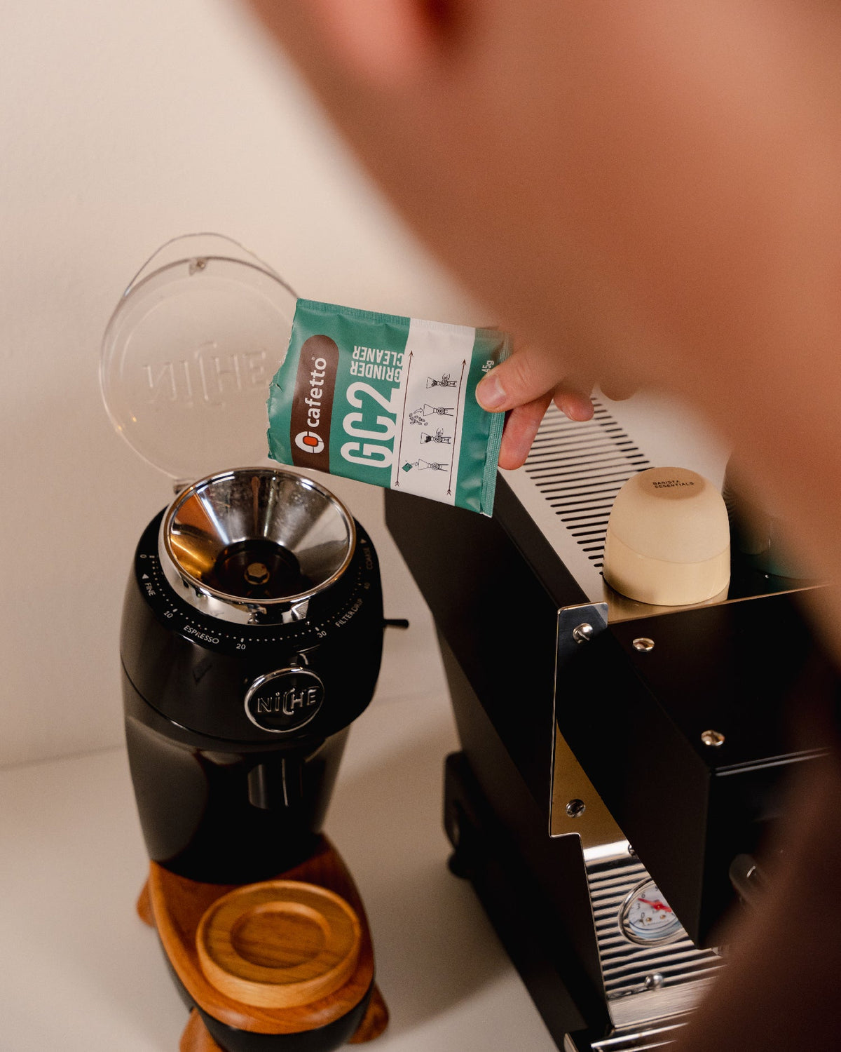 Een zakje Cafetto Grinder Clean wordt in een koffiemolen geleegd