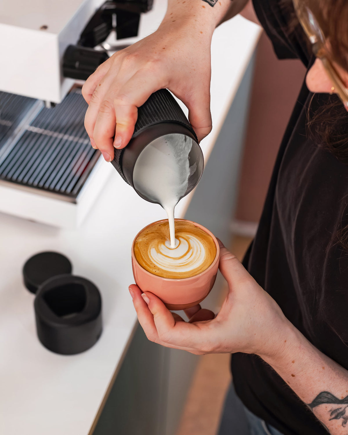 Latte art schenken met een zwarte handvatloze melkkan