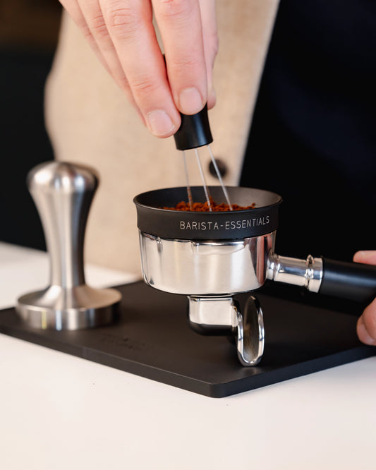 Portafilter op de grote zwarte tampermat met hoek tijdens het verdelen van koffie