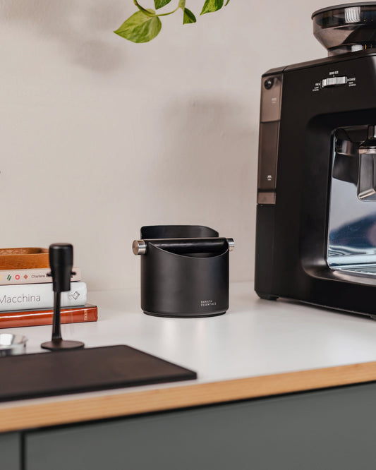 11 cm zwarte uitklopbak op het werkblad naast een koffiemachine