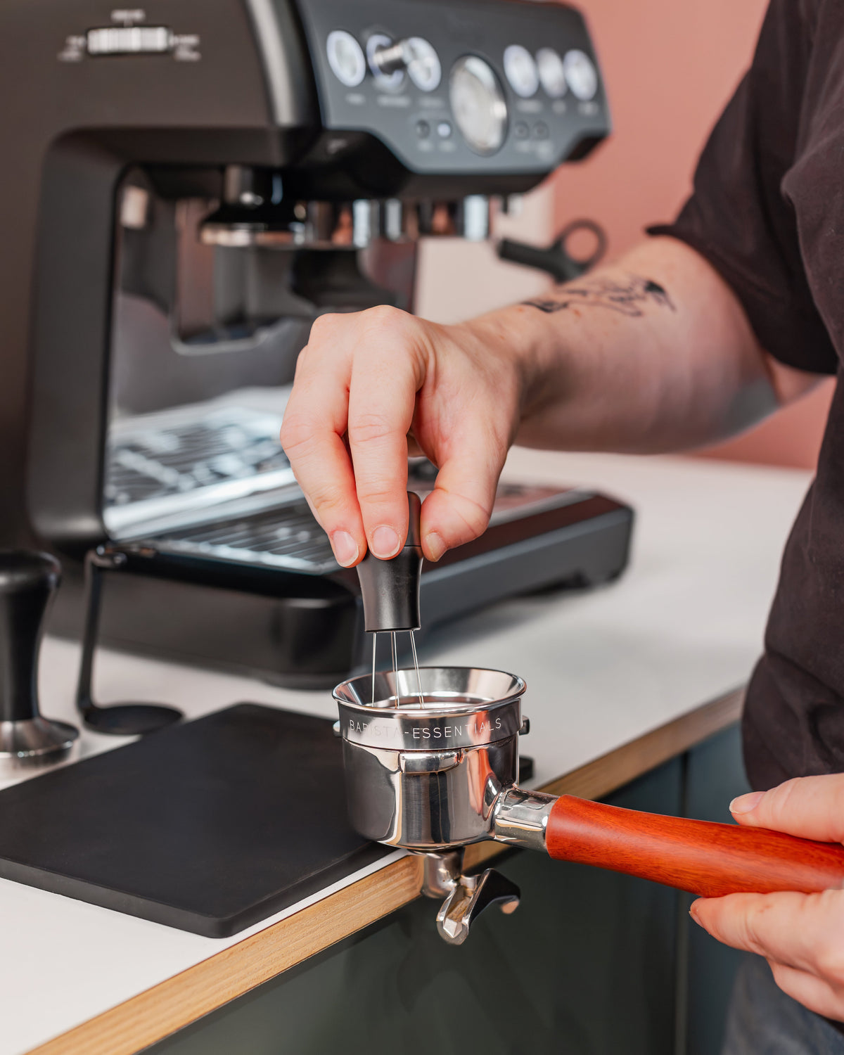 Zilveren doseerring van 53,3 mm op een filterdrager tijdens het verdelen van koffie met naaldjes