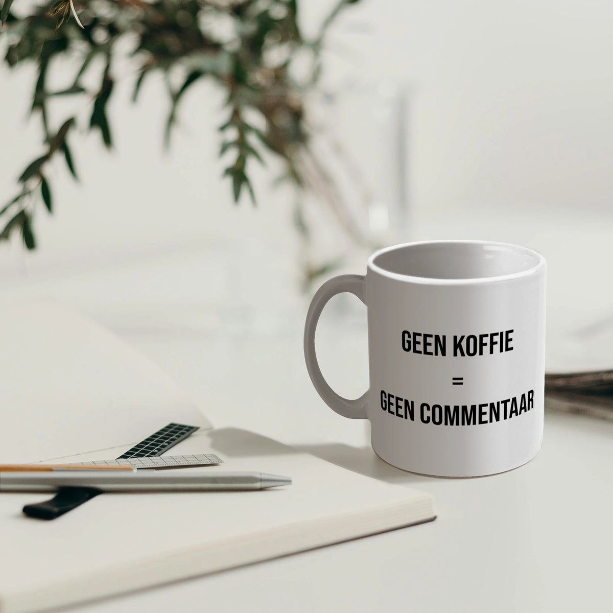 Koffiemok met dubbelzijdige tekst “Geen koffie = geen commentaar”, zichtbaar voor iedereen.