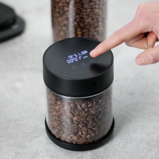 Hand bedient de Pro-deksel op een glazen bus met koffiebonen