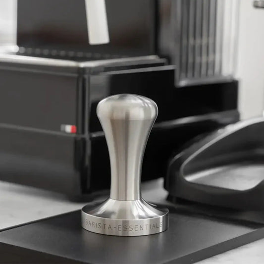 RVS tamper naast een espressomachine