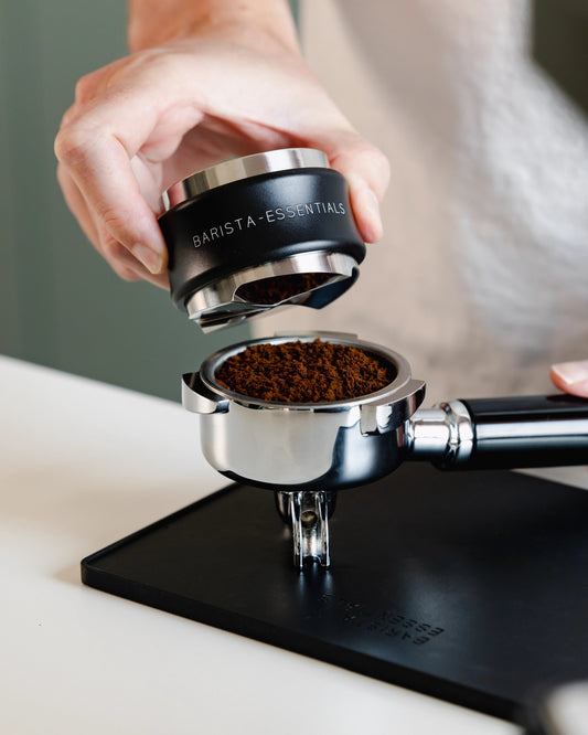 Zwarte koffieverdeler boven een filterbakje met gemalen koffie