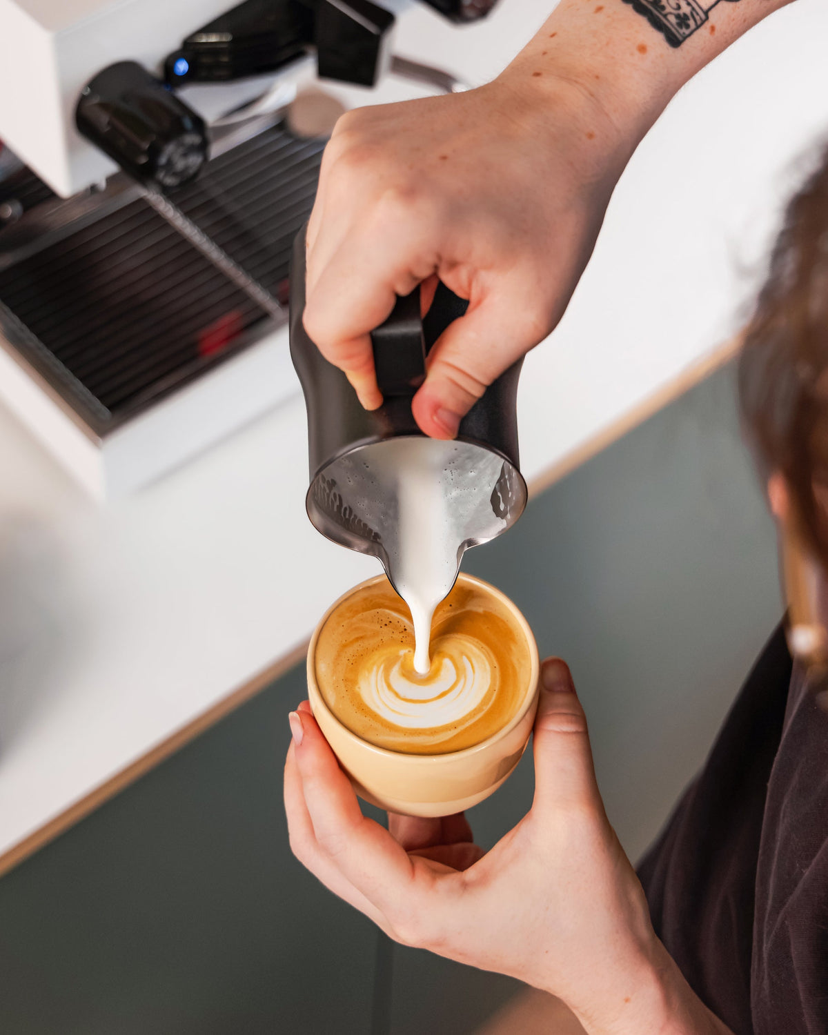 Melk wordt uit een zwarte Italiaanse melkkan 500 ml in een kop koffie geschonken