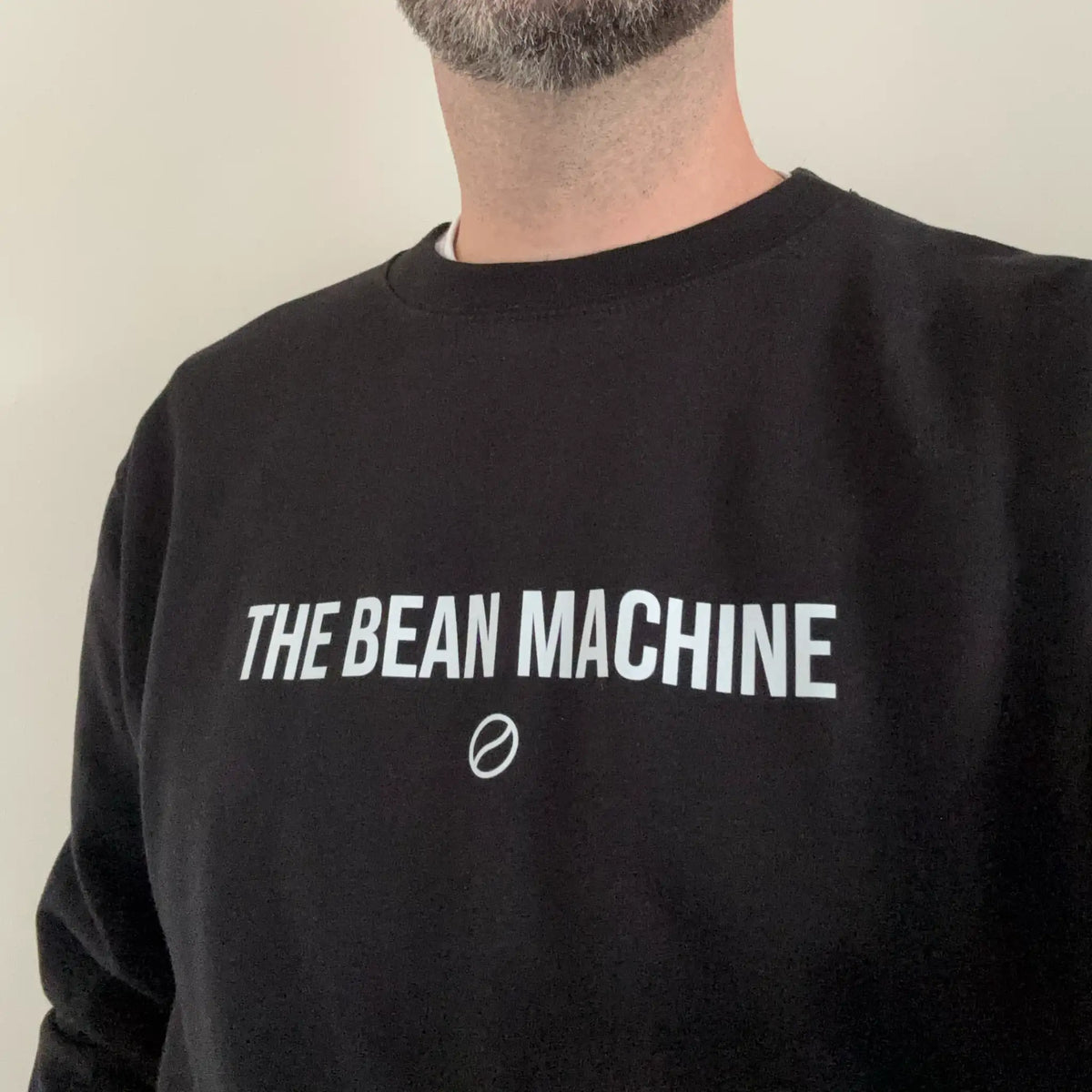 Zwarte Coffee Crew sweater voor barista’s en koffieliefhebbers in een thuisbarista-setting met espressomachine en espresso.