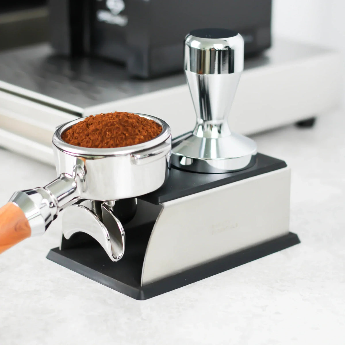 Top 10 essentiële barista tools voor thuisbarista met koffieweegschaal, melkkan, vacuüm voorraadpot, uitklopbak en reinigingstools naast een espressomachine.