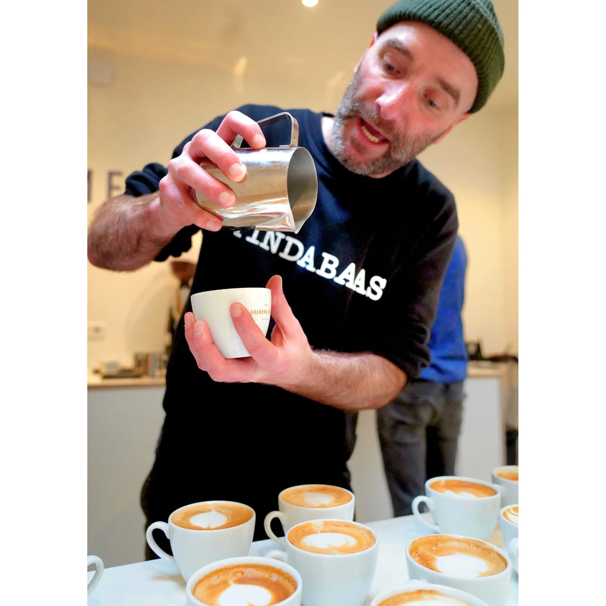Close-up van de barista-coach die een latte art schenkbeweging demonstreert.