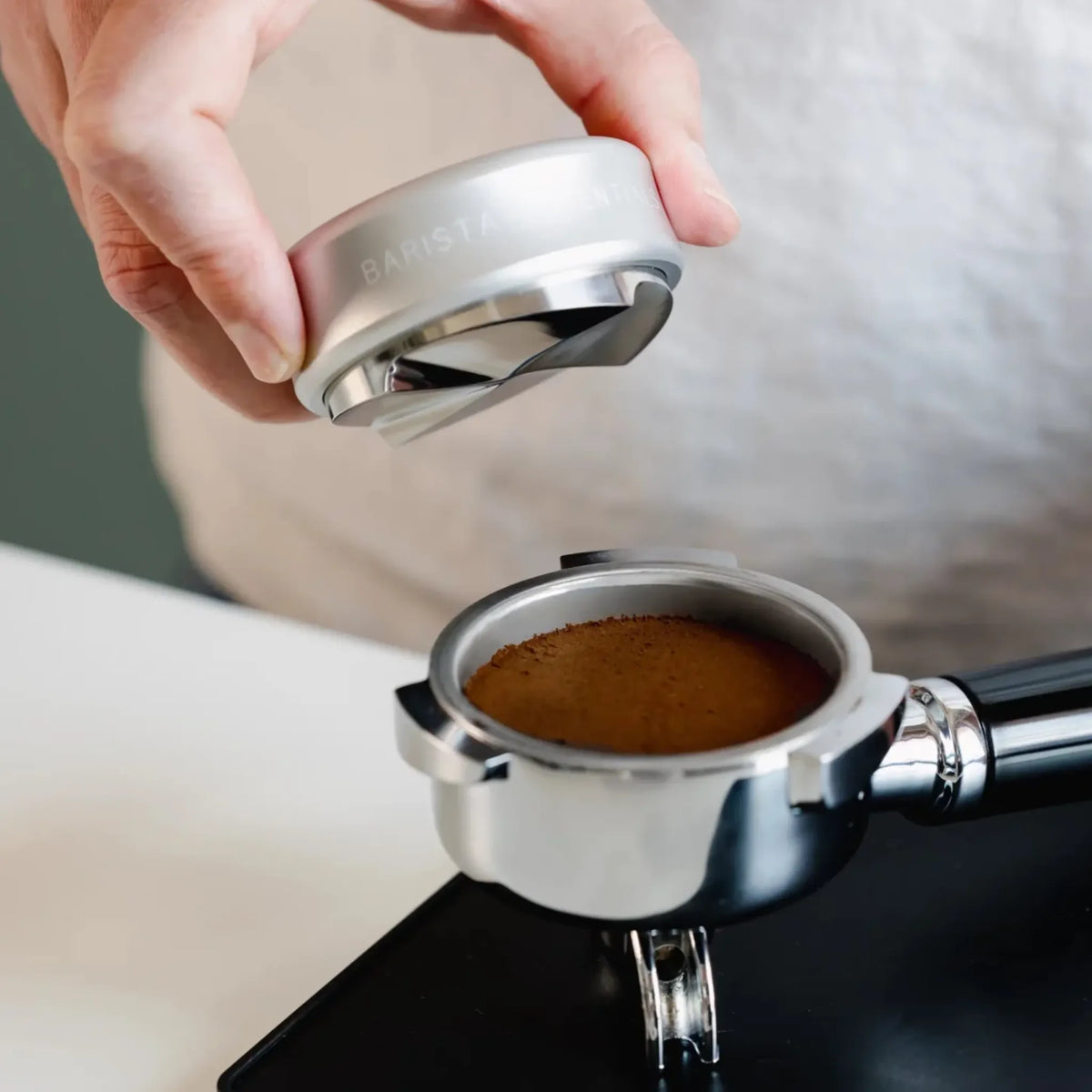 Zilverkleurige koffieverdeler boven een vlak gemaakt koffiebed