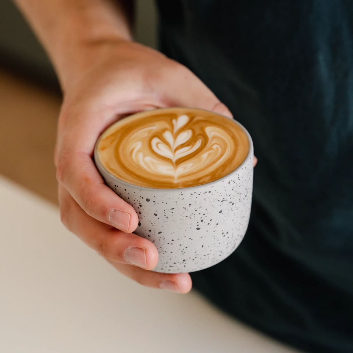 Barista toont zelfgemaakte latte art in handgemaakt 250ml latte kopje tijdens oefensessie.