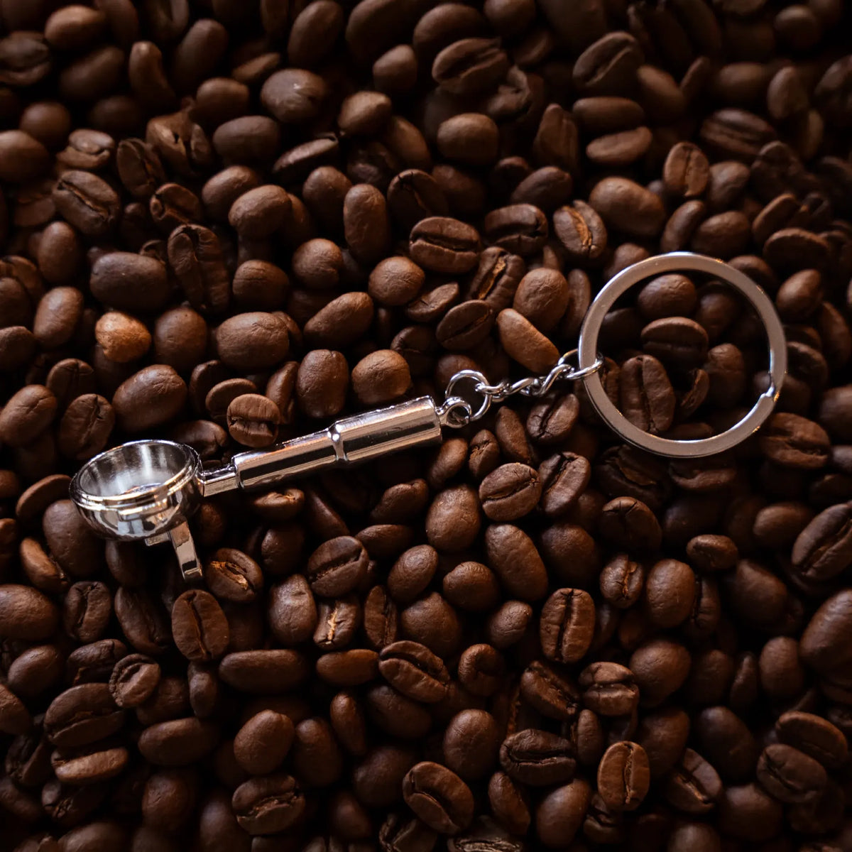 Filterdrager-sleutelhanger met donker handvat op koffiebonen