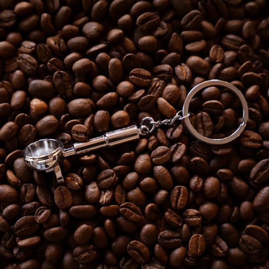 Filterdrager-sleutelhanger met donker handvat op koffiebonen