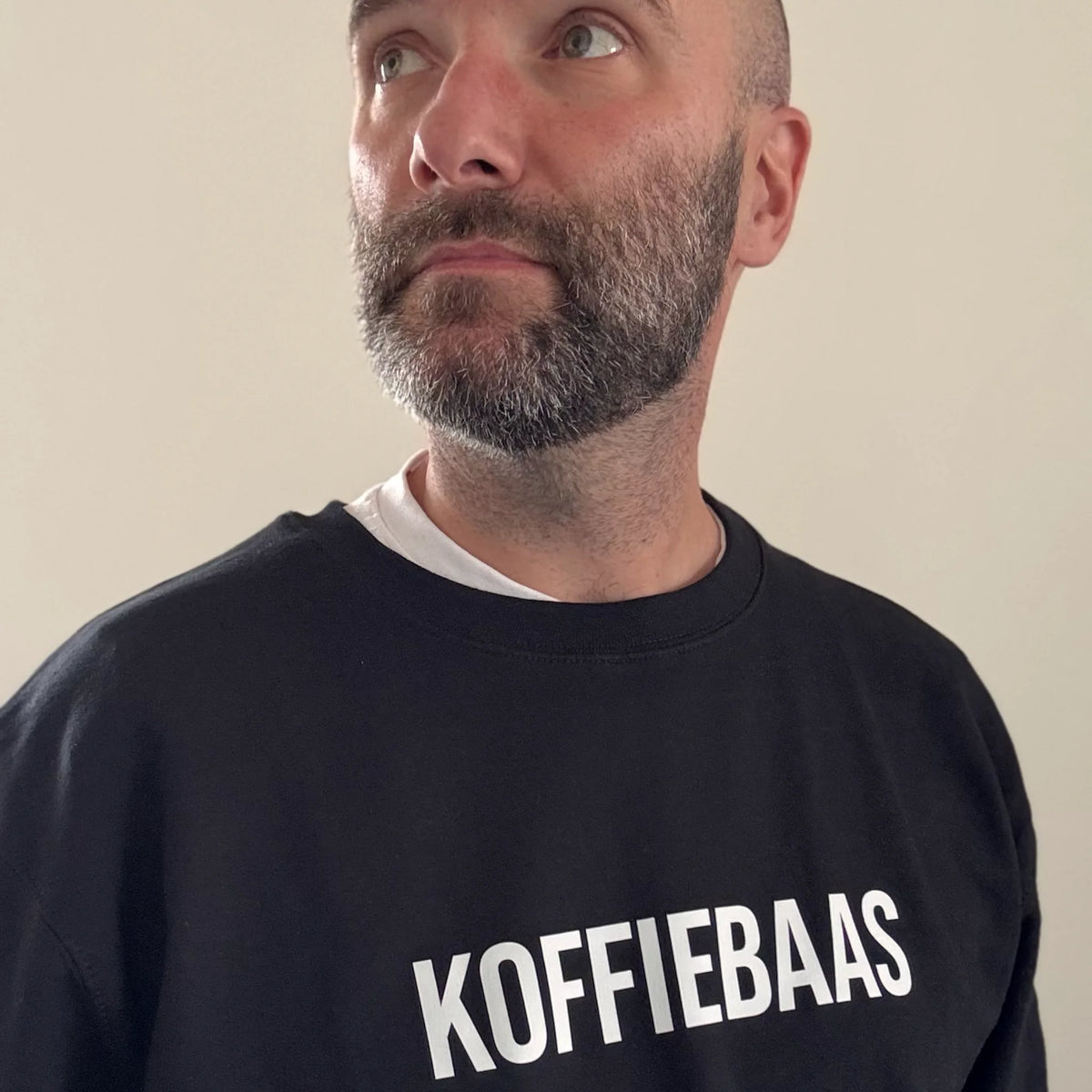 Man draagt zwarte “KOFFIEBAAS” sweater – ideaal barista cadeau