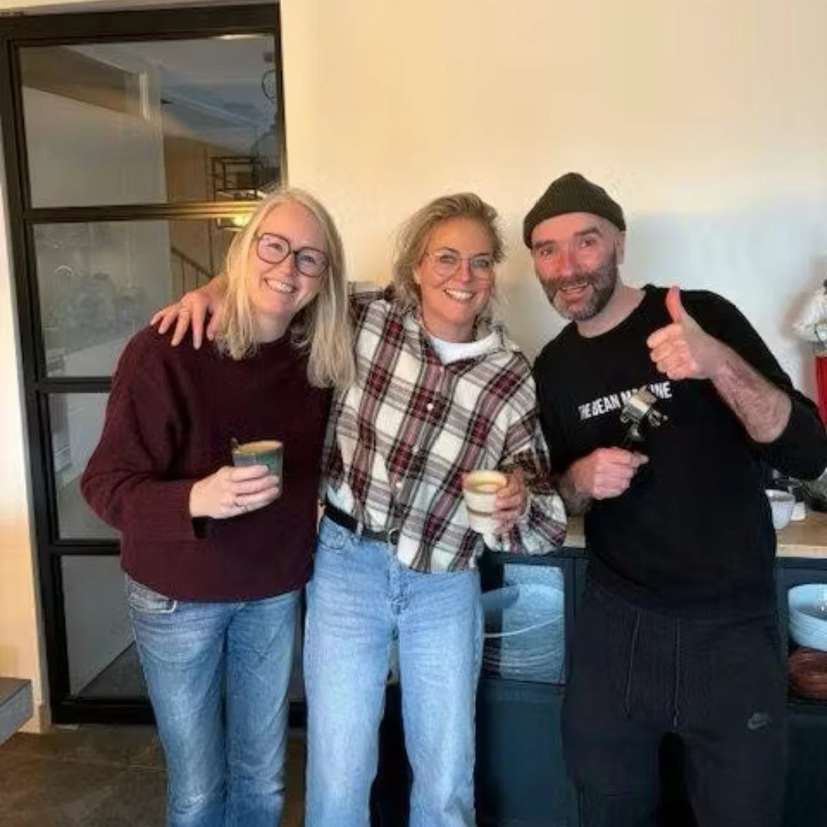 Barista workshop aan huis met espressomachine, drie deelnemers houden vers gezette espresso vast tijdens een persoonlijke koffietraining onder begeleiding van Geertjandebaristaman in een huiselijke keukenomgeving