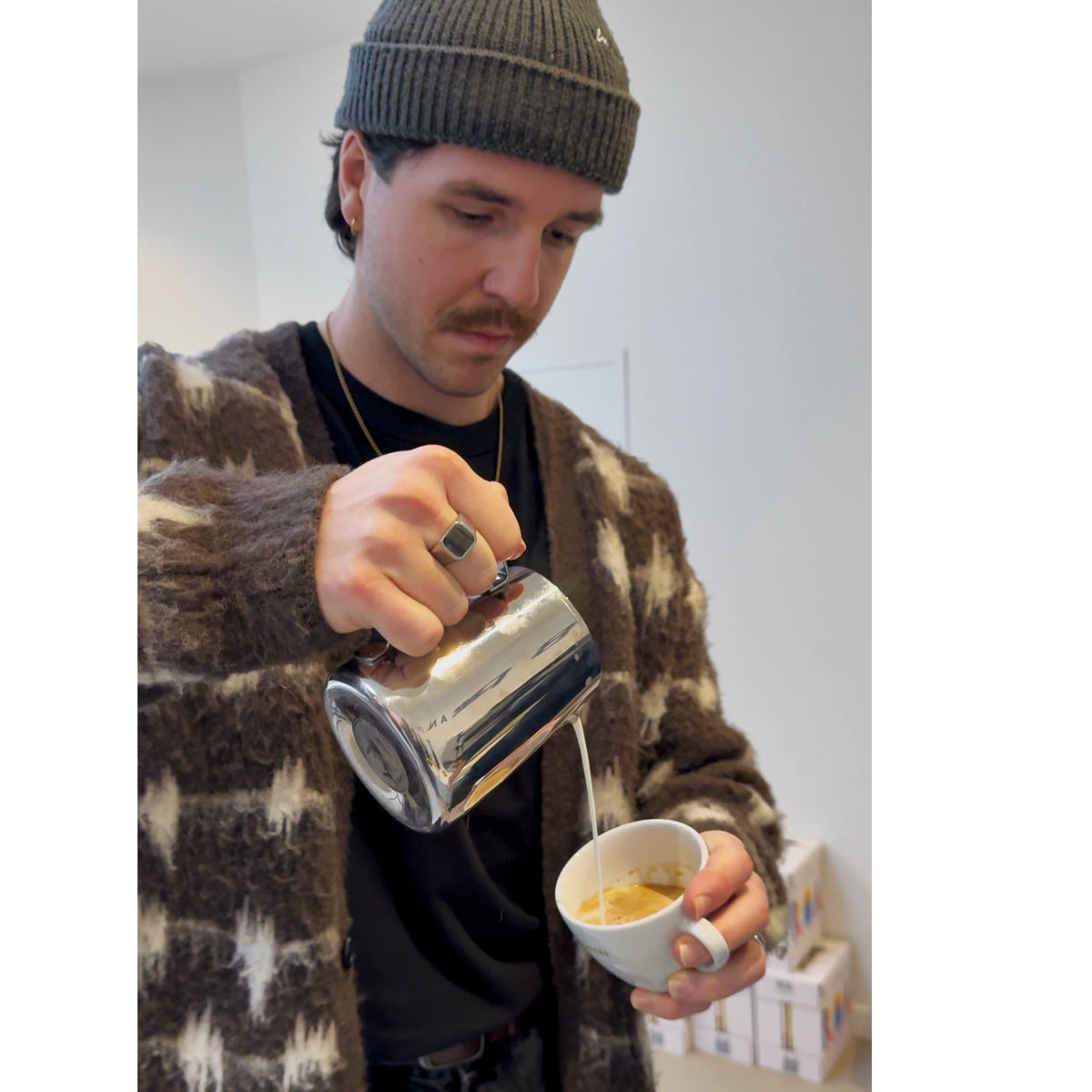 Een barista workshop deelnemer maakt latte art in een cappuccino kopje