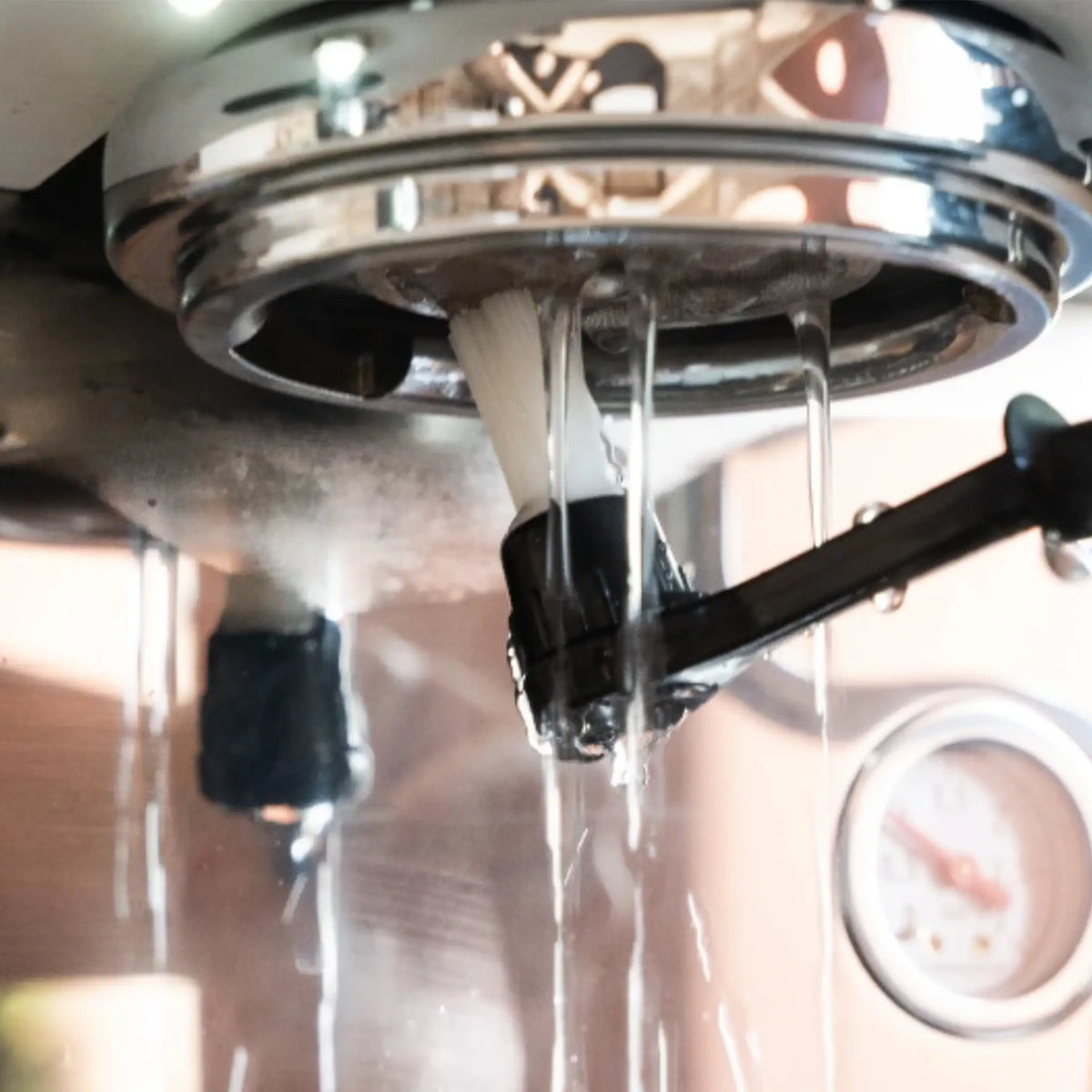 Reinigingsborstel in gebruik bij een espressomachine, voor grondige schoonmaak van de zetgroep.