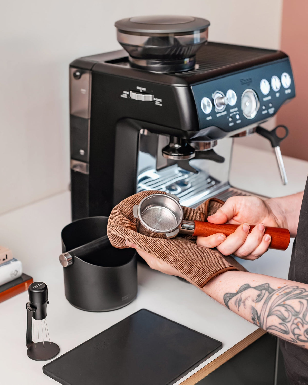 Een hand maakt een filterbakje schoon met een bruin barista-doekje