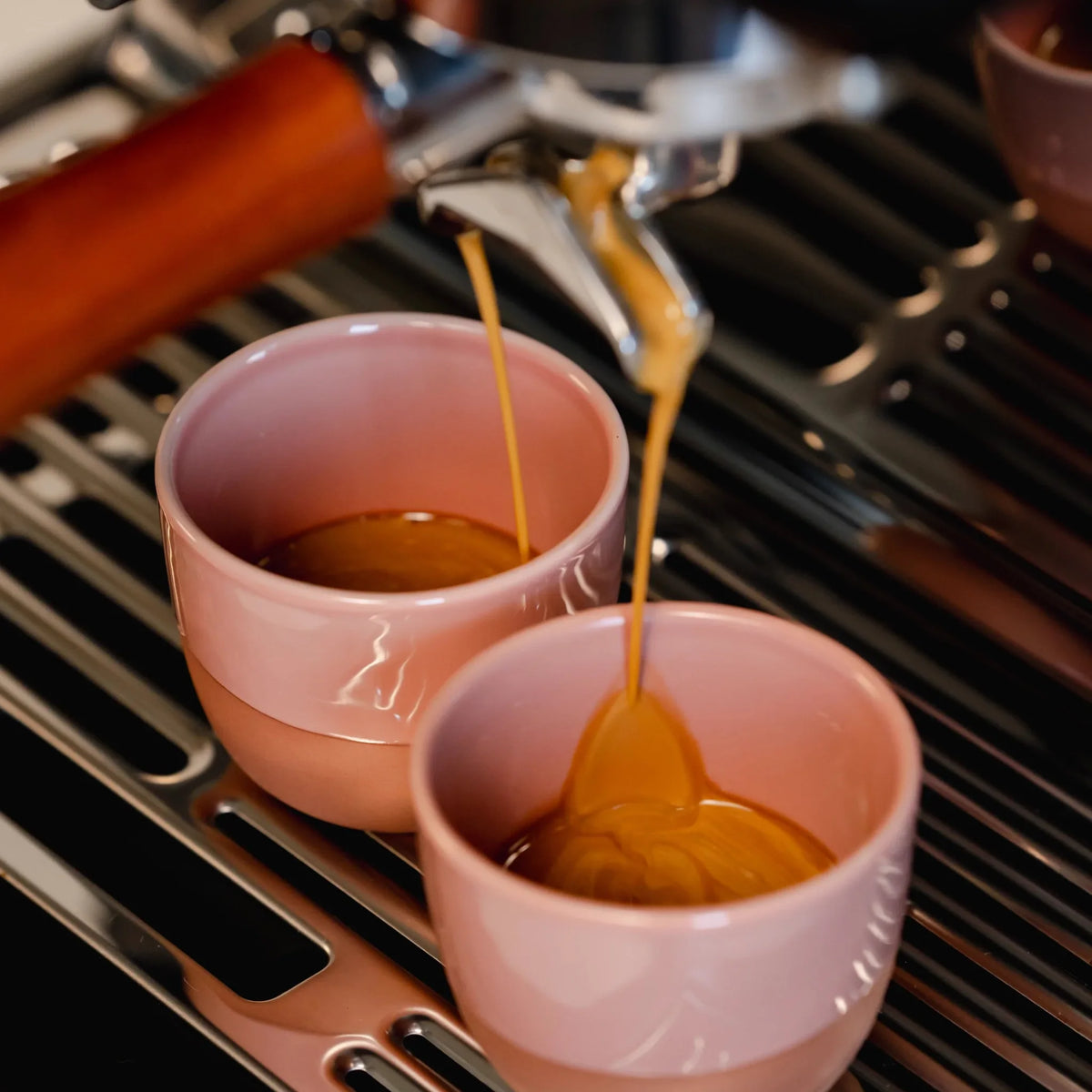 Espresso stroomt in twee roze kopjes