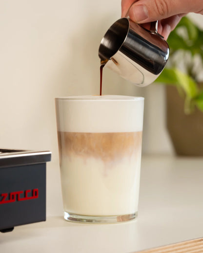 Espresso uit het kannetje in een latte macchiato schenken