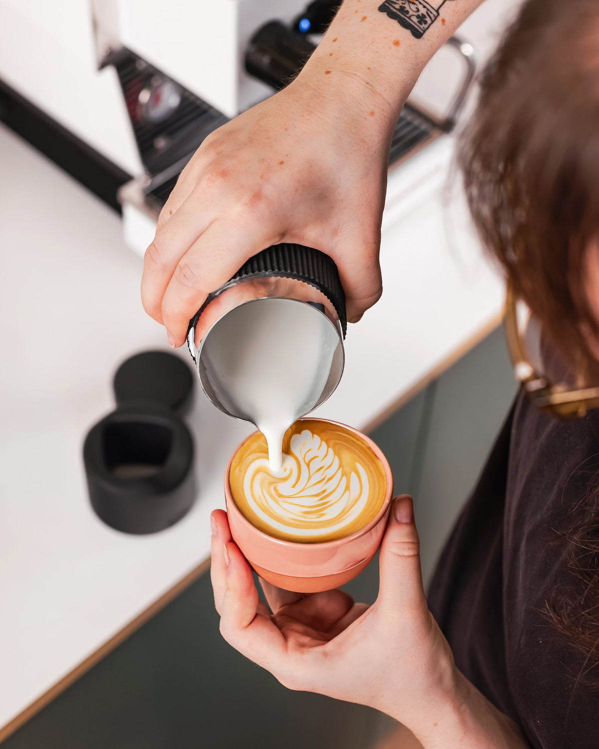 Cappuccino inschenken met een zilveren handvatloze melkkan