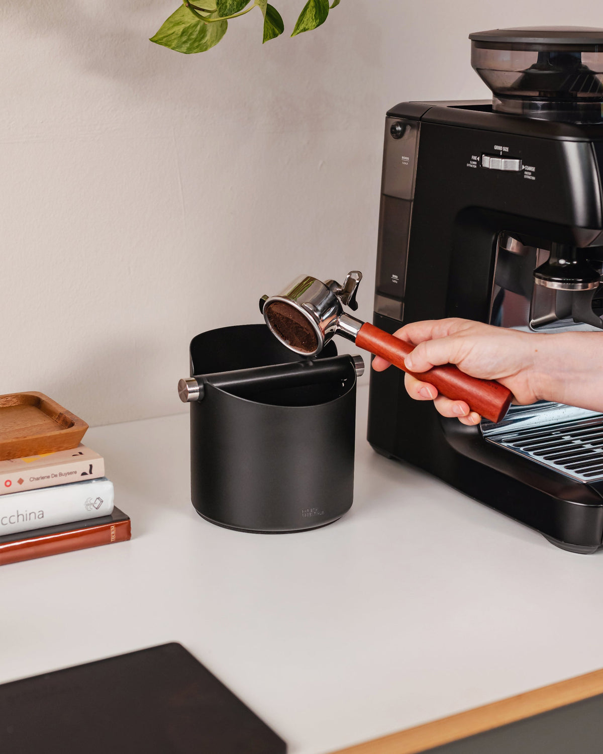 14 cm zwarte uitklopbak tijdens het uitkloppen van een koffiepuck