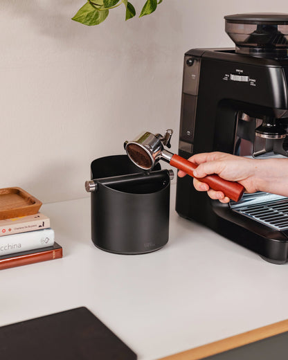 14 cm zwarte uitklopbak tijdens het uitkloppen van een koffiepuck