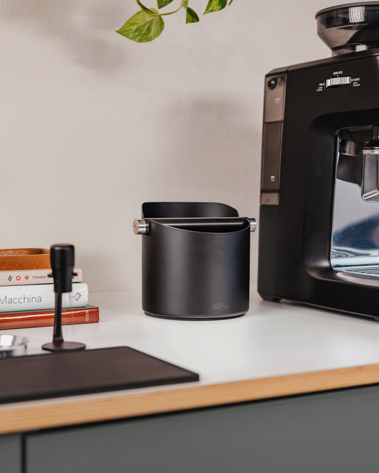 14 cm zwarte uitklopbak op het werkblad naast een koffiemachine