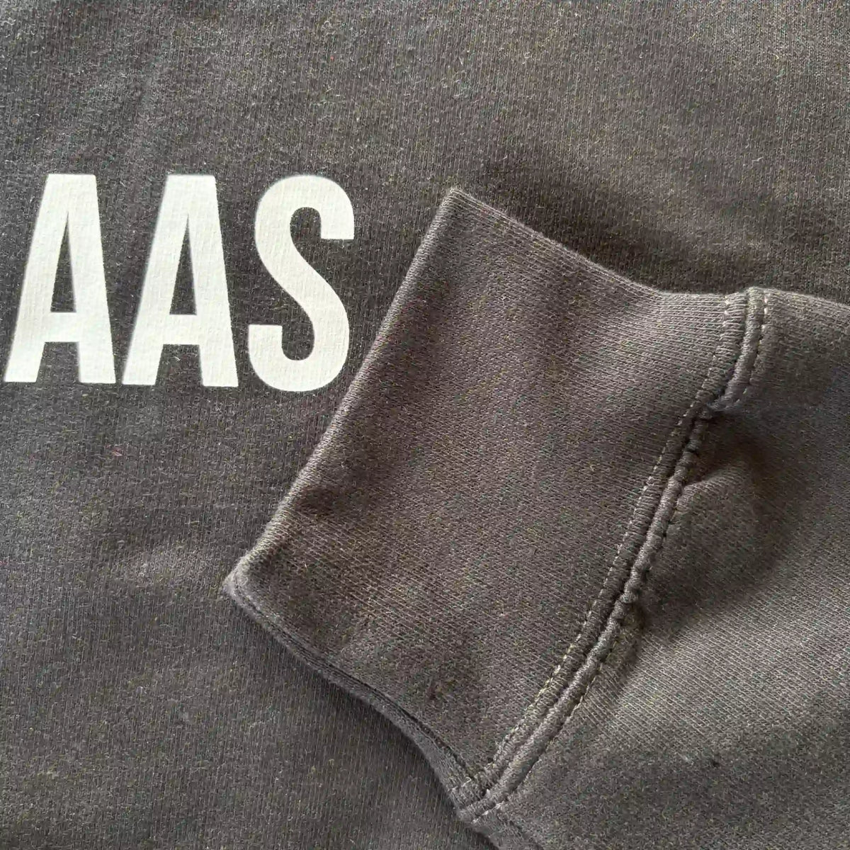 Detail van mouw en opdruk van het zwarte “KOFFIEBAAS” sweatshirt voor koffieliefhebbers