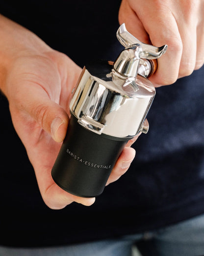 Handen houden een filterdrager op de zwarte 51 mm doseerbeker