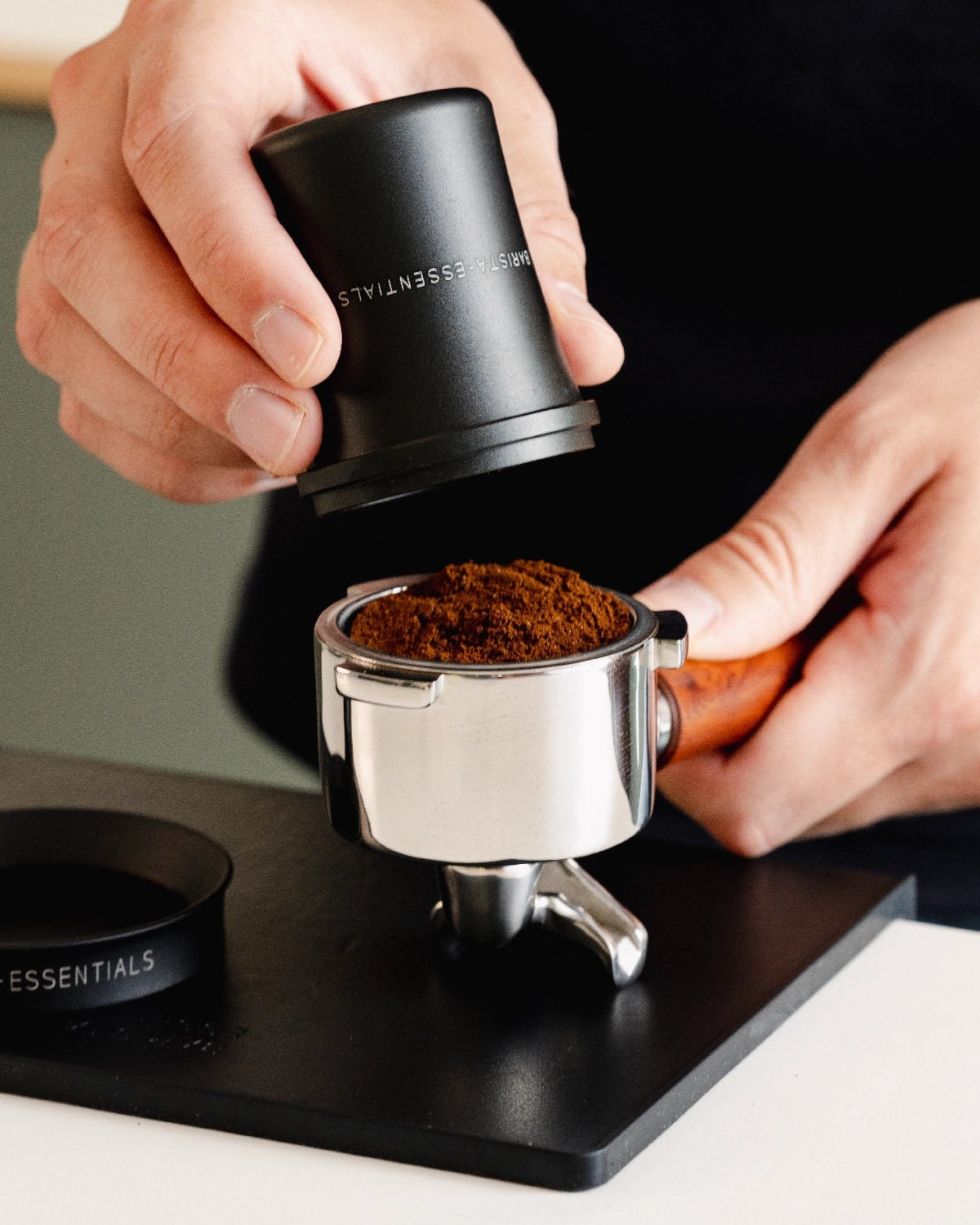 Koffie uit een zwarte 51 mm doseerbeker wordt in een filterbakje overgezet