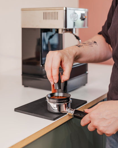 Zwarte doseerring van 58 mm tijdens het verdelen van gemalen koffie in een filterdrager
