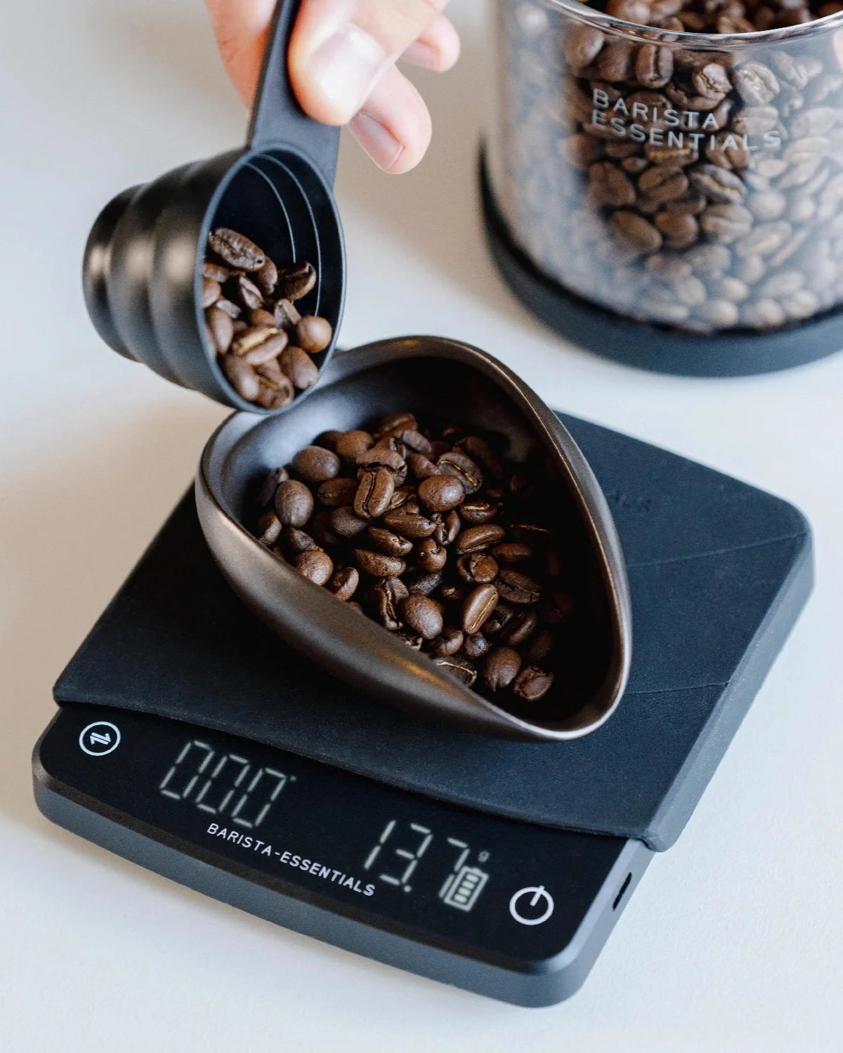 Koffiebonen worden in een keramische doseerschaal op een weegschaal geschonken