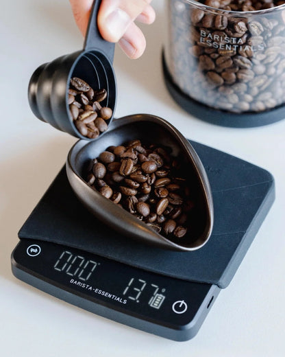 Koffiebonen worden in een keramische doseerschaal op een weegschaal geschonken