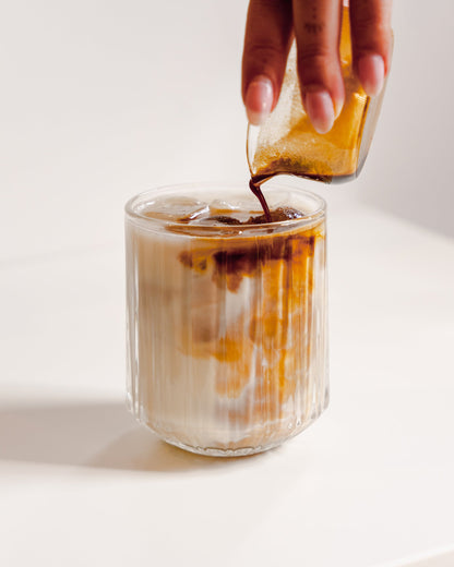 Espresso wordt in een geribbeld glas met melk en ijs geschonken
