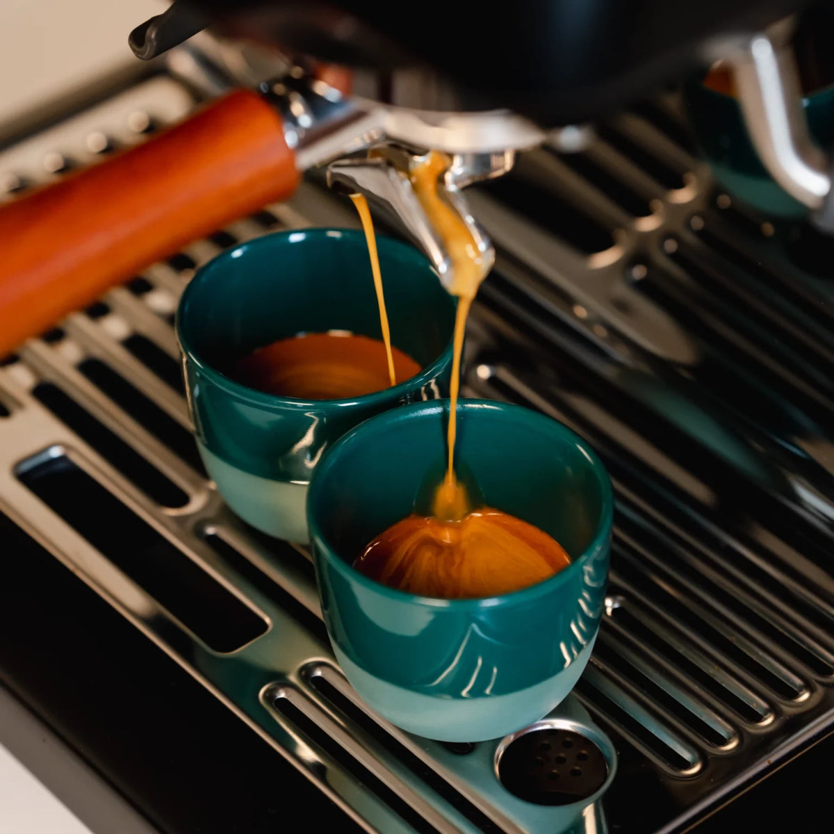 Espresso stroomt in groene kopjes onder de uitloop van een espressomachine