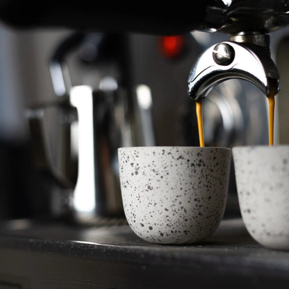 Espresso stroomt uit de machine in een gestippeld kopje