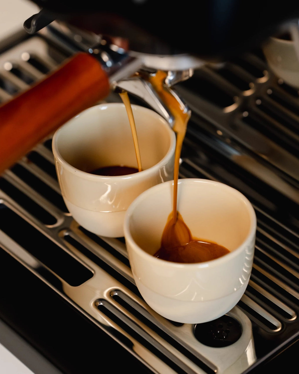 Espresso stroomt in twee lichte kopjes onder een portafilter