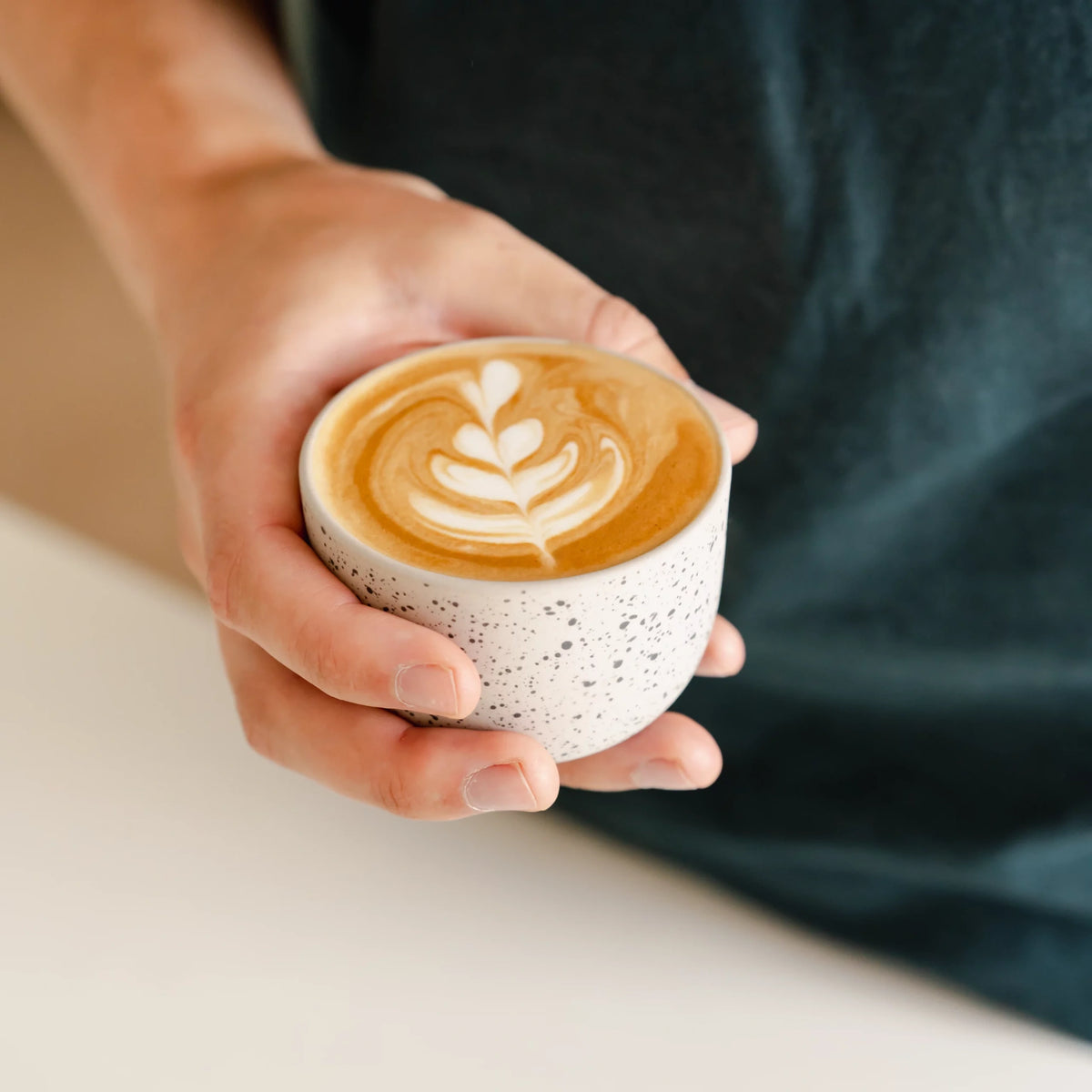 Handen houden een cappuccino met latte art