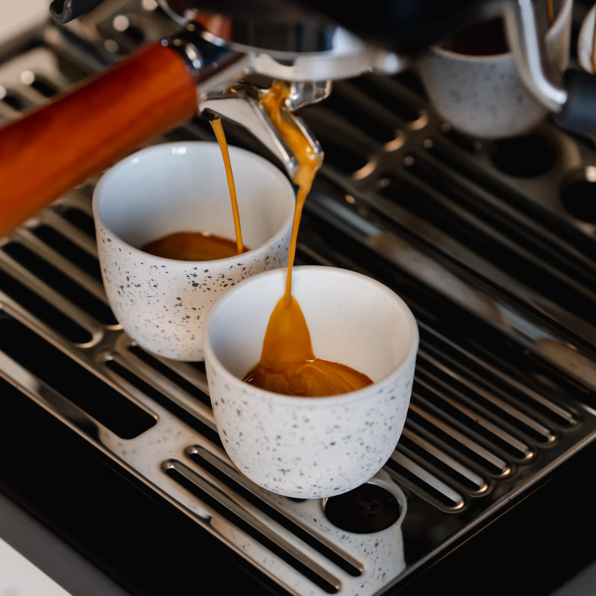 Espresso stroomt in twee kopjes onder een portafilter