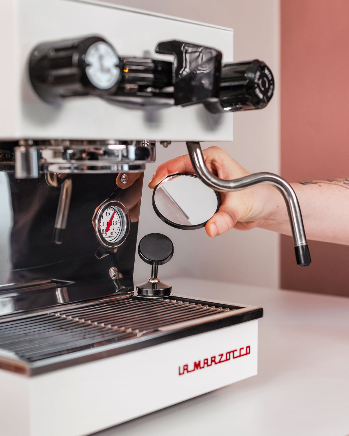 Kantelbare shot mirror naast een espressomachine met stoompijp
