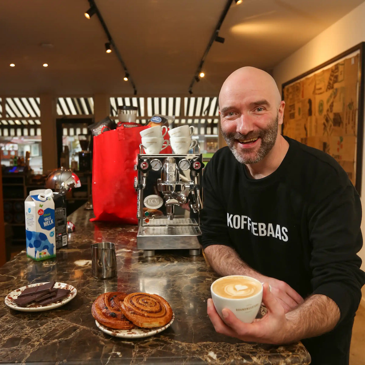 Geert-Jan van der Molen geeft privé barista coaching aan huis en serveert een latte tijdens een persoonlijke espresso workshop met professionele espressomachine.