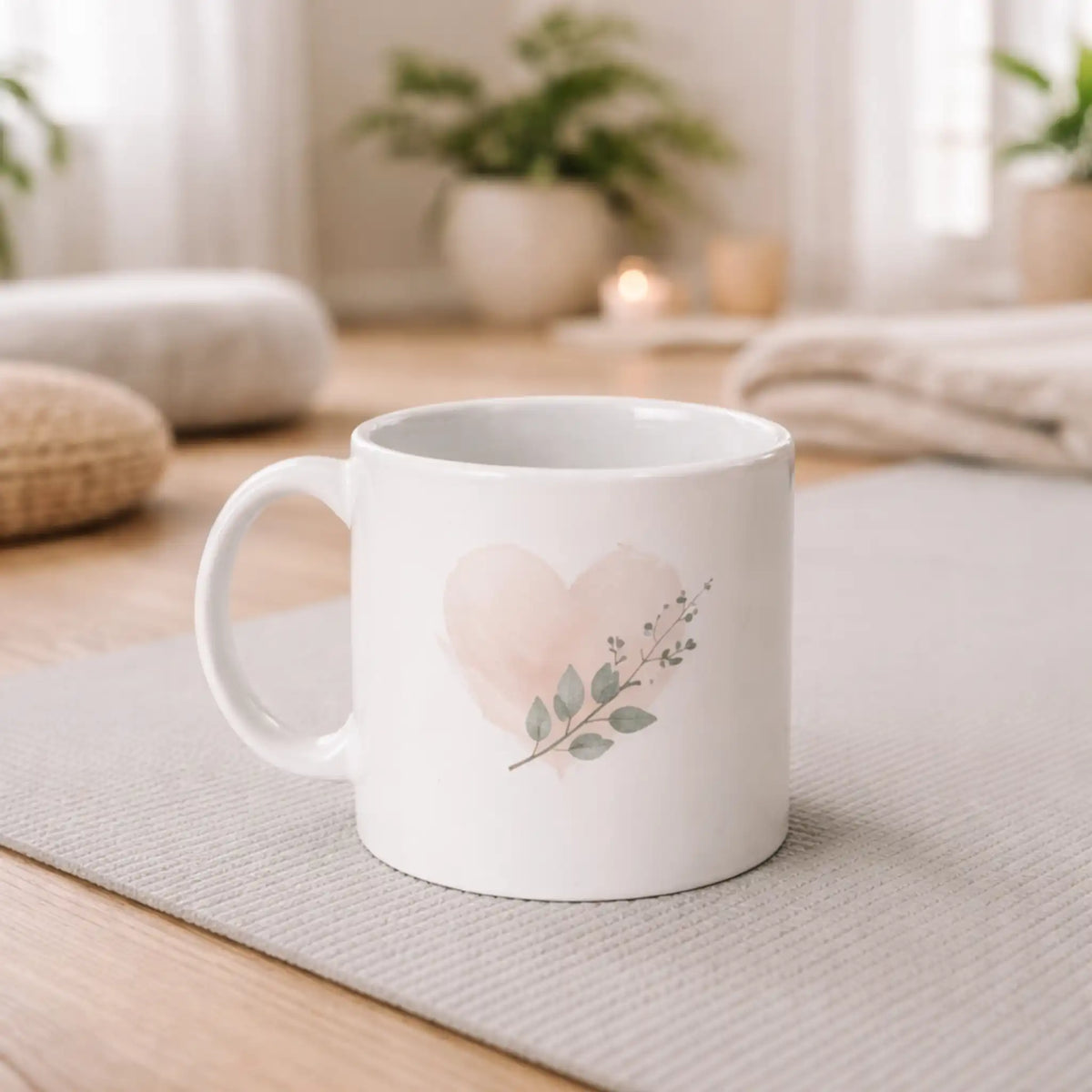 Witte mok met hartje en bladeren op een yogamat, gebruikt in een rustige yoga- of meditatieruimte.