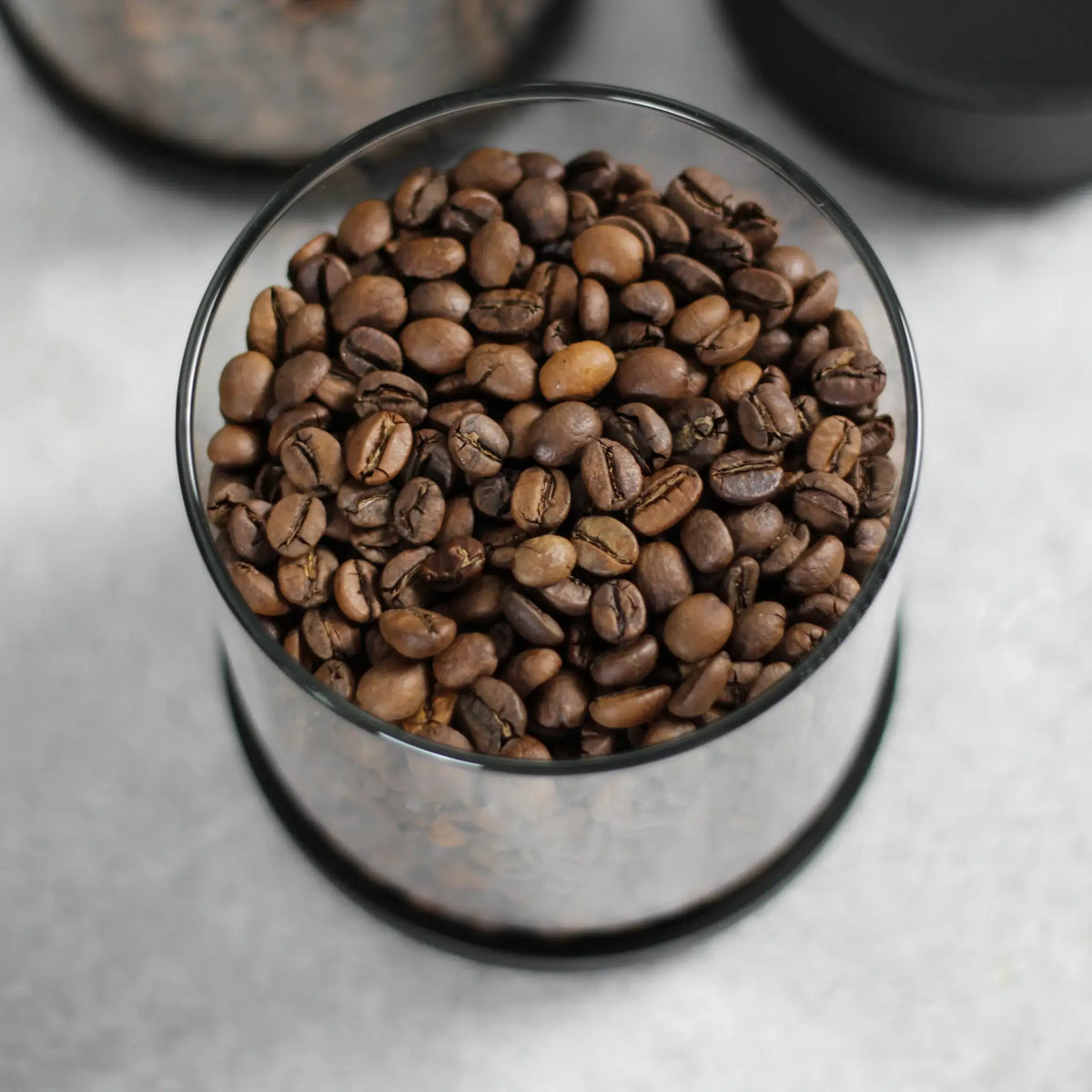 Bovenaanzicht van koffiebonen in een geopende glazen koffiebus