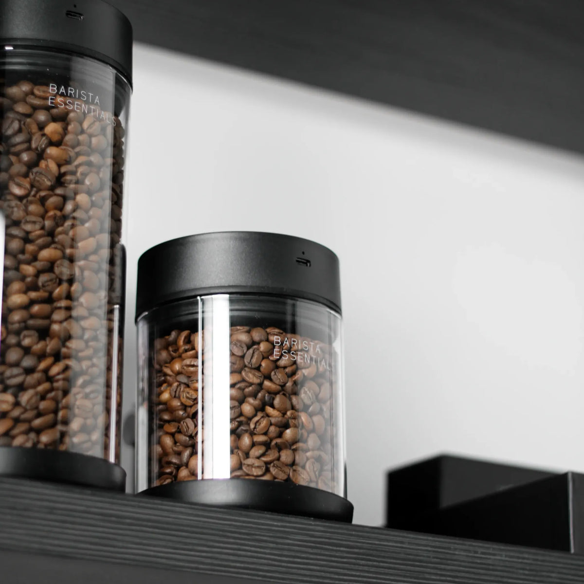 Glazen koffiebussen in verschillende hoogtes met zwarte deksels