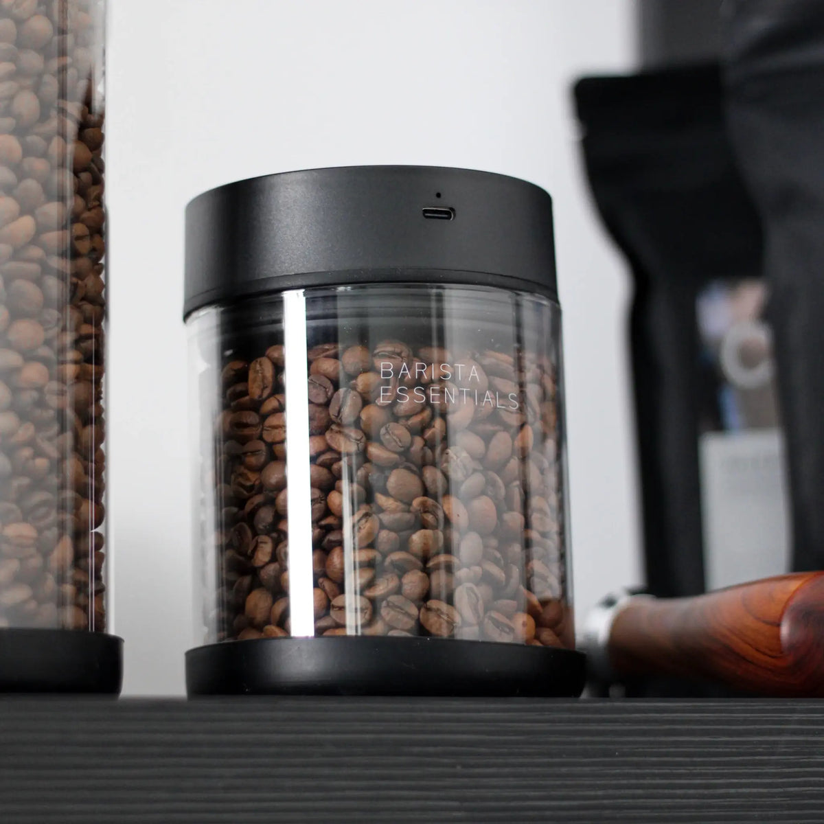 Glazen koffiebus met zwarte deksel en hele koffiebonen