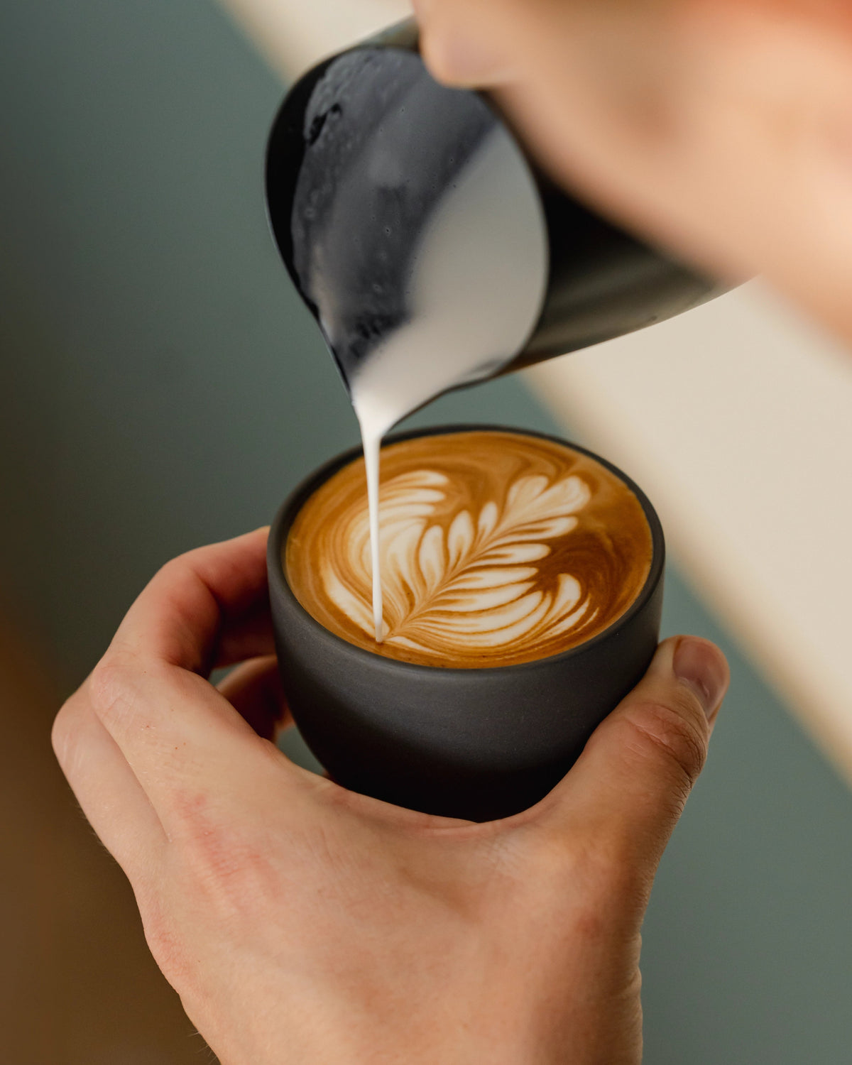 Melk wordt in een grijs cappuccinokopje geschonken