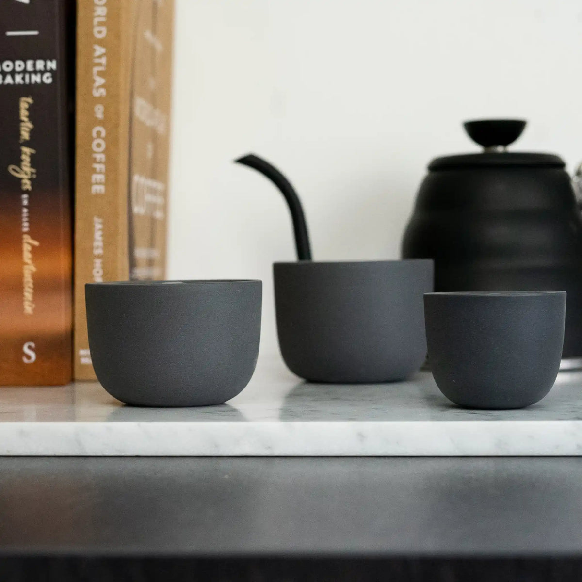 Grijze kopjes op een werkblad naast koffieaccessoires