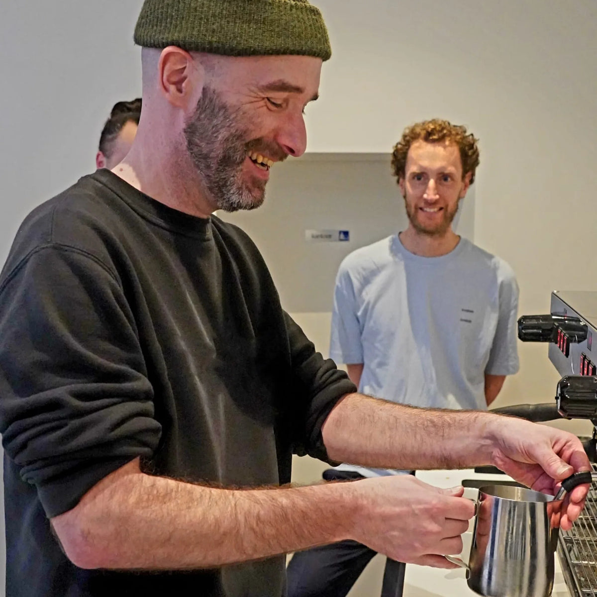 barista laat de techniek van het schuimen van melk zien aan een groep tijdens een barista workshop