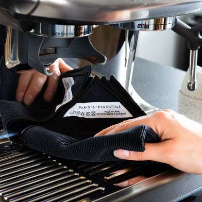Hand houdt een zwarte doek bij de espressomachine